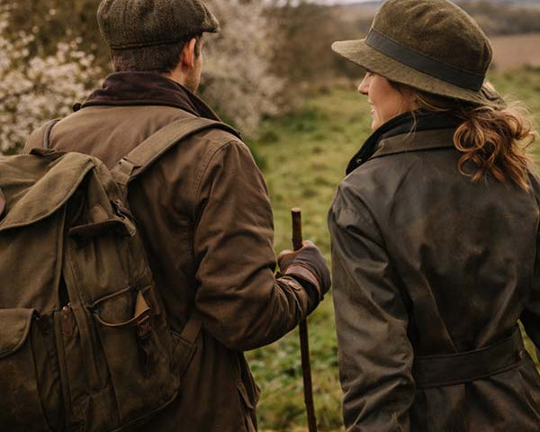 Couple wearing country walking accessories including hats and gloves walking through the British countryside.