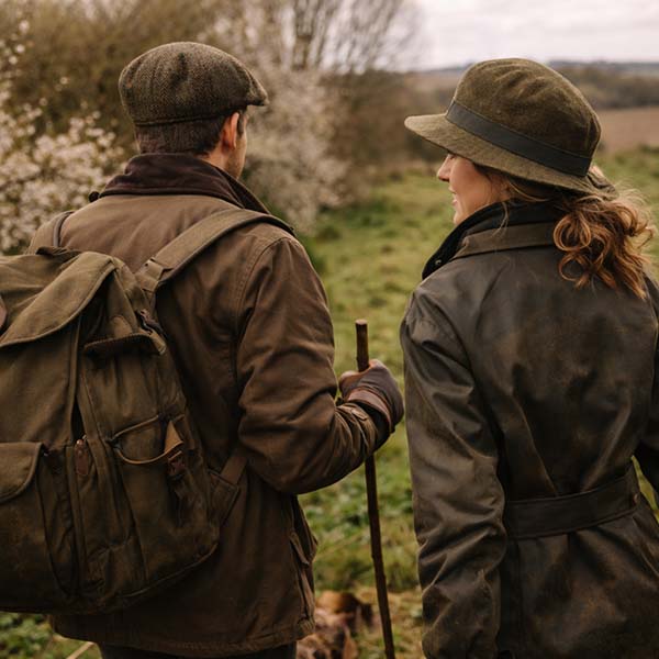 Couple wearing country walking accessories including hats and gloves walking through the British countryside.